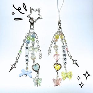 May include: Two beaded charms with silver chains, star-shaped clasps, and decorative charms. One charm spells "RIKU" and the other "SUNOO" with colorful beads, hearts, bows, and butterflies. The charms are on a white background.