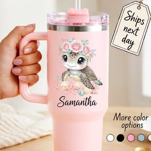 May include: A pink insulated tumbler with a handle, featuring a cartoon turtle wearing a floral crown. The turtle is surrounded by seashells and the name "Samantha" is printed below. The tumbler has a straw and a lid. The tag says "Ships next day".
