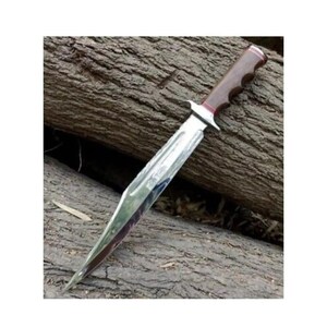 K&ouml;nnte beinhalten: Ein silbernes Messer mit einem braunen Holzgriff und einer roten Spitze. Das Messer liegt auf einem St&uuml;ck Holz.