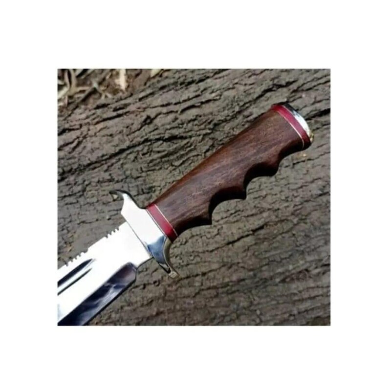 K&ouml;nnte beinhalten: Nahaufnahme eines Jagdmessers mit braunem Holzgriff und silberner Klinge. Der Griff hat eine rote Akzentlinie und einen strukturierten Griff.