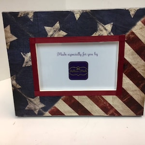 May include: A red, white, and blue American flag picture frame with a red mat and a white inner frame. The frame has the text "Made especially for you by Ribbon Made" inside the frame.