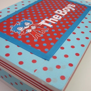 May include: A blue and red polka dot box with a blue ribbon and a white label that says "The Boys". The label has a picture of three characters from the book "The Cat in the Hat".