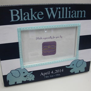 May include: A white and navy blue striped picture frame with a light blue border. The frame has a light blue elephant design and the text "Blake William", "Made especially for you by Ribbon-Made", "April 4, 2014", and "7 lbs 1 oz - 19 in".