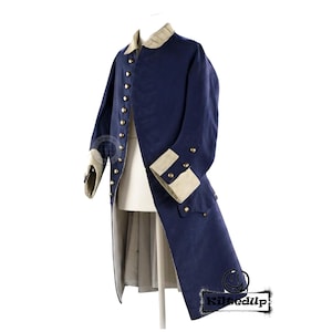 Op de afbeelding: Een marineblauwe historische jas met gouden knopen, een beige kraag en manchetten. De lange jas wordt op een mannequin gepresenteerd en toont zijn op maat gemaakte ontwerp en periode-correcte details. De jaslengte reikt tot aan de knieën.