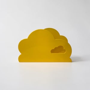 May include: A bright yellow cloud-shaped desk organizer with a small cloud cutout. The organizer is made of a solid material and has a smooth finish. The design is simple and modern, suitable for a desk or shelf.