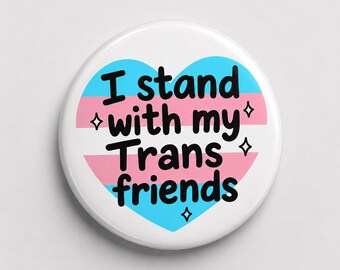 May include: A round pin-back button featuring a heart-shaped design with horizontal stripes in light blue, pink, and white. The black text reads I stand with my Trans friends, accented by four small black four-pointed star symbols.