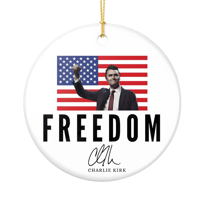 May include: White ceramic ornament with a gold string for hanging. The ornament features an image of a man in a suit with the American flag behind him. The word "FREEDOM" is printed in large black letters.