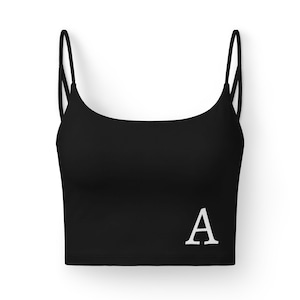 May include: Black crop top with thin spaghetti straps and a white letter "A" printed on the front. The top is a solid black color and appears to be made of a soft material. The design is simple and minimalist.