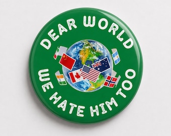 May include: A circular green pin-back button featuring a central image of the Earth surrounded by various national flags. The white text printed in a circular arc around the graphic reads, "DEAR WORLD WE HATE HIM TOO" in a distressed, bold font.