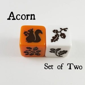 May include: Set of two orange and white dice with black acorn and squirrel designs. The dice are labeled "Acorn" and "Set of Two".