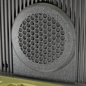 May include: A black speaker with a hexagonal grill. The speaker is mounted on a textured surface.