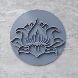 May include: A gray plastic cookie cutter in the shape of a lotus flower.