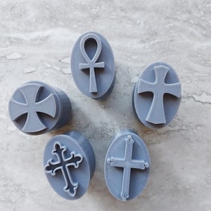 May include: Five gray rubber stamps with different religious symbols. The symbols include a cross, a Celtic cross, and an ankh.