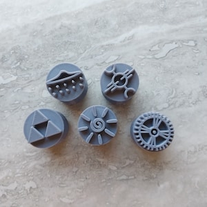 May include: Six grey round rubber stamps with different designs. The designs include a UFO, a sun, a gear, a triangle, and two abstract designs.