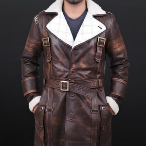 May include: A brown leather coat with a white shearling collar and lining. The coat features a belted waist, multiple pockets, and decorative buckles. The coat has a vintage, distressed look.
