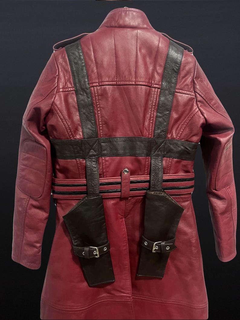May include: A burgundy leather jacket with black accents, featuring a high collar, shoulder epaulets, and a belted waist. The jacket has two attached holster-like pockets with buckle closures, and padded shoulder details.