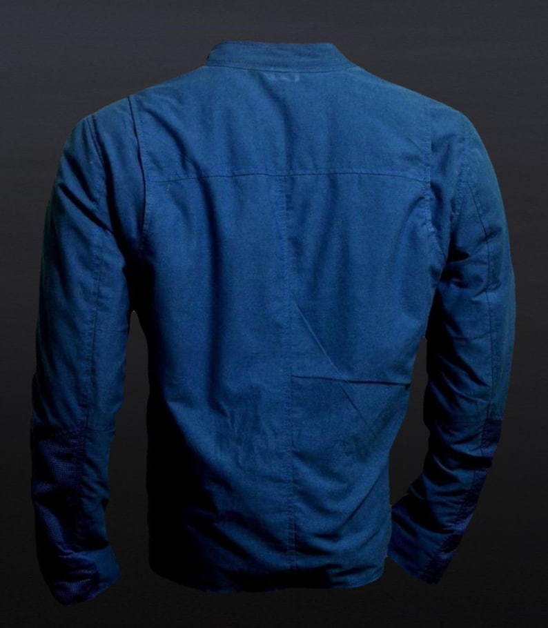 May include: A blue jacket with long sleeves and a mandarin collar. The back of the jacket is visible, showcasing the tailored seams and a subtle pocket detail. The jacket is made of a textured fabric.