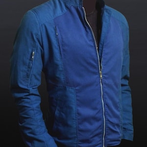 May include: A blue jacket with a full-length zipper and a stand-up collar. The jacket has a ribbed texture on the front panel and a zippered pocket on the left sleeve. The jacket is a solid blue color.