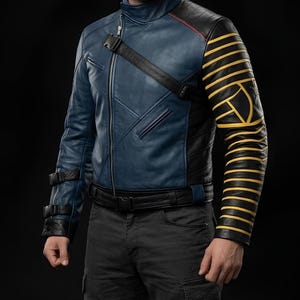 May include: A blue and black leather jacket with yellow striped accents on the right sleeve. The jacket has a high collar, a zipper closure, and black straps. The jacket is worn with dark grey trousers.