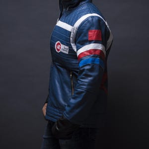 Puede incluir: Chaqueta de cuero azul con detalles en blanco, rojo y azul. La chaqueta presenta un dise&ntilde;o acolchado en los hombros y un parche "Dead Pegasus". Tiene cierre de cremallera y guantes negros.