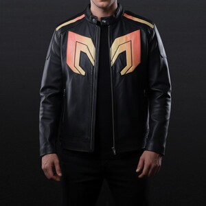 Puede incluir: Chaqueta de cuero negra con cuello mandarín y cierre de cremallera frontal. La chaqueta presenta diseños geométricos naranjas y amarillos en el pecho y los hombros. Una prenda de abrigo elegante y moderna.