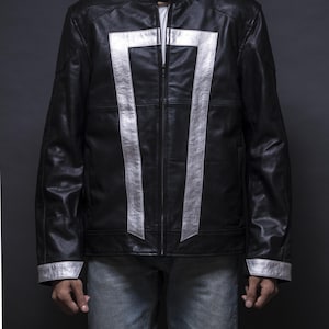 May include: Black leather jacket with silver accents. The jacket features a silver design on the front and sleeves. It has a zipper closure and a round collar. The jacket is paired with blue jeans.