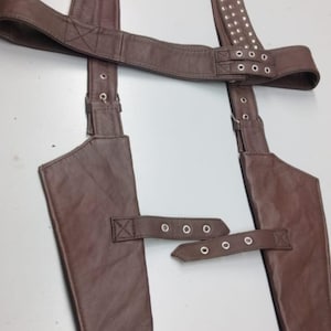 May include: Brown leather detachable gun holster and belt with silver rivets. The holster has two pouches and adjustable straps. The text at the bottom says "detachable gun holster and belt (optional)".