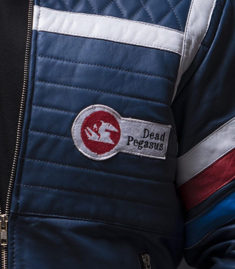 Puede incluir: Chaqueta de cuero azul marino con detalles en blanco y rojo. La chaqueta presenta un dise&ntilde;o acolchado y un parche con la inscripci&oacute;n "Dead Pegasus" y un logotipo rojo y blanco. Una cremallera recorre la parte delantera.