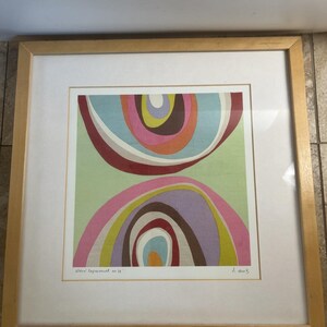 May include: A square framed print featuring an abstract design of concentric, curved shapes in shades of pink, light blue, lime green, brown, and yellow against a pale green background. The print is titled "Color Experiment no 28" and signed.