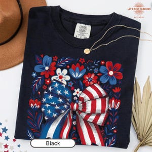Boho floral American flag bow t-shirt on Comfort Colors 1717 unisex tee. Patriotic 4th of July shirt for women featuring red white and blue bow with floral design. Available in sizes S, M, L, XL, 2XL, 3XL, 4XL and multiple color options including ivory, white, navy, pepper, blossom, and chambray. Perfect America 250th Anniversary tee, Independence Day outfit, summer BBQ, and casual Americana style.