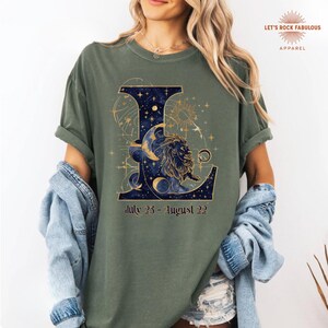 Leo Zodiac Sign celestial lion graphic on a Comfort Colors 1717 t-shirt featuring gold moon phases, stars, and cosmic artwork with July 23–August 22 text. Astrology-inspired graphic tee available in multiple colors and sizes S to 4XL. Perfect gift for Leo birthdays, horoscope lovers, and boho celestial fashion.