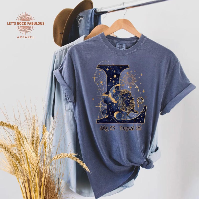 Leo Zodiac Sign celestial lion graphic on a Comfort Colors 1717 t-shirt featuring gold moon phases, stars, and cosmic artwork with July 23–August 22 text. Astrology-inspired graphic tee available in multiple colors and sizes S to 4XL. Perfect gift for Leo birthdays, horoscope lovers, and boho celestial fashion.