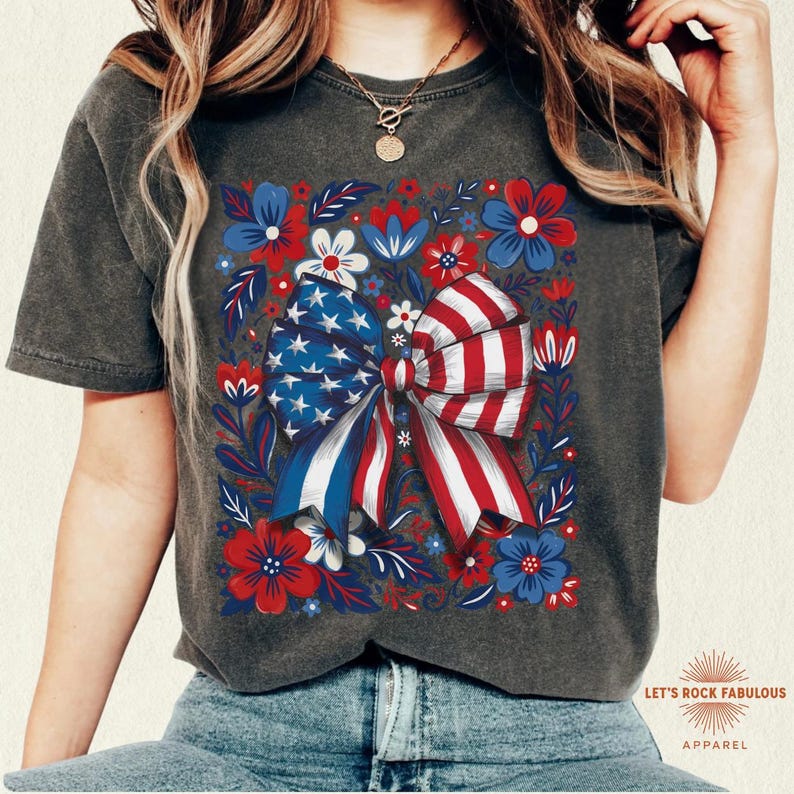 Boho floral American flag bow t-shirt on Comfort Colors 1717 unisex tee. Patriotic 4th of July shirt for women featuring red white and blue bow with floral design. Available in sizes S, M, L, XL, 2XL, 3XL, 4XL and multiple color options including ivory, white, navy, pepper, blossom, and chambray. Perfect America 250th Anniversary tee, Independence Day outfit, summer BBQ, and casual Americana style.
