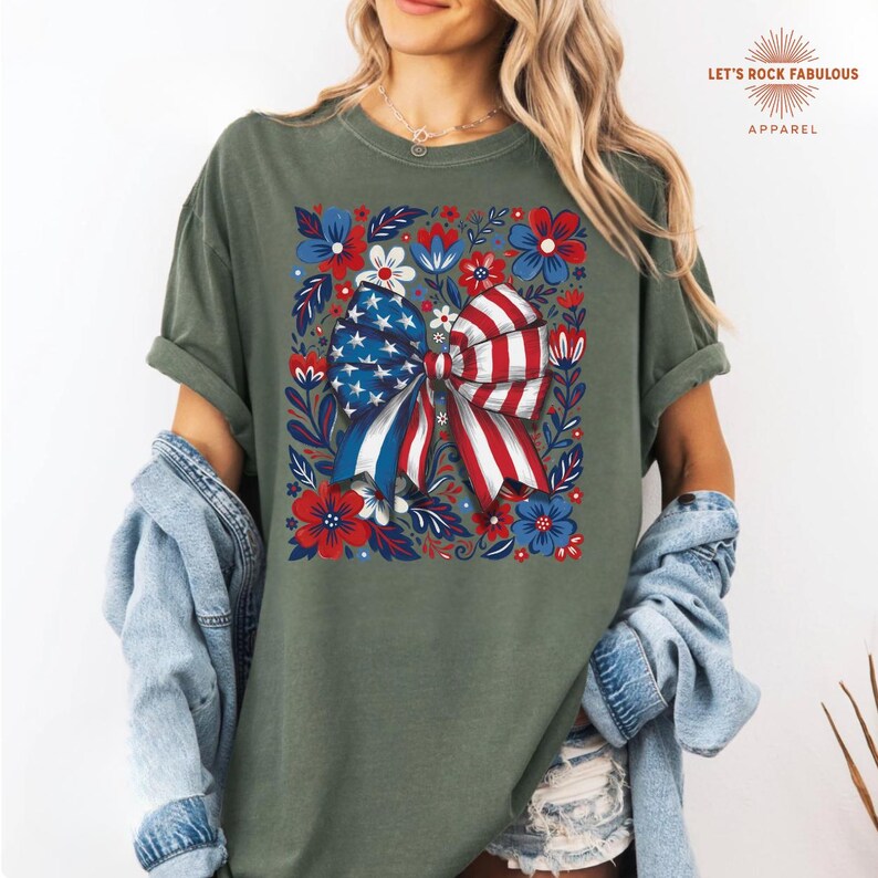 Boho floral American flag bow t-shirt on Comfort Colors 1717 unisex tee. Patriotic 4th of July shirt for women featuring red white and blue bow with floral design. Available in sizes S, M, L, XL, 2XL, 3XL, 4XL and multiple color options including ivory, white, navy, pepper, blossom, and chambray. Perfect America 250th Anniversary tee, Independence Day outfit, summer BBQ, and casual Americana style.