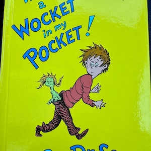 May include: A children's book cover with the title "There's a Wocket in my Pocket!" in blue text on a yellow background. The illustration features a cartoon boy with a creature emerging from his pocket. The author's name, Dr. Seuss, is at the bottom.