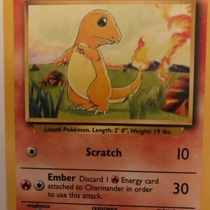 Puede incluir: Una carta Pok&eacute;mon Charmander de la primera edici&oacute;n del Juego de Cartas Coleccionables Pok&eacute;mon. La carta presenta una ilustraci&oacute;n de Charmander, un peque&ntilde;o Pok&eacute;mon parecido a un lagarto naranja con una llama en la cola. La carta tiene un fondo blanco con texto negro y un borde rojo. El nombre de la carta, "Charmander", est&aacute; impreso en letras grandes y negritas en la parte superior de la carta. La carta tiene 50 PS. La carta tiene dos ataques: "Rasgu&ntilde;o" por 10 de da&ntilde;o y "Ascuas" por 30 de da&ntilde;o. La debilidad de la carta es el agua, y su coste de retirada es una carta de energ&iacute;a incolora. El texto de la carta dice: "Obviamente prefiere los lugares calientes. Si se le atrapa en la lluvia, se dice que el vapor sale de la punta de su cola. LV. 10 #4".