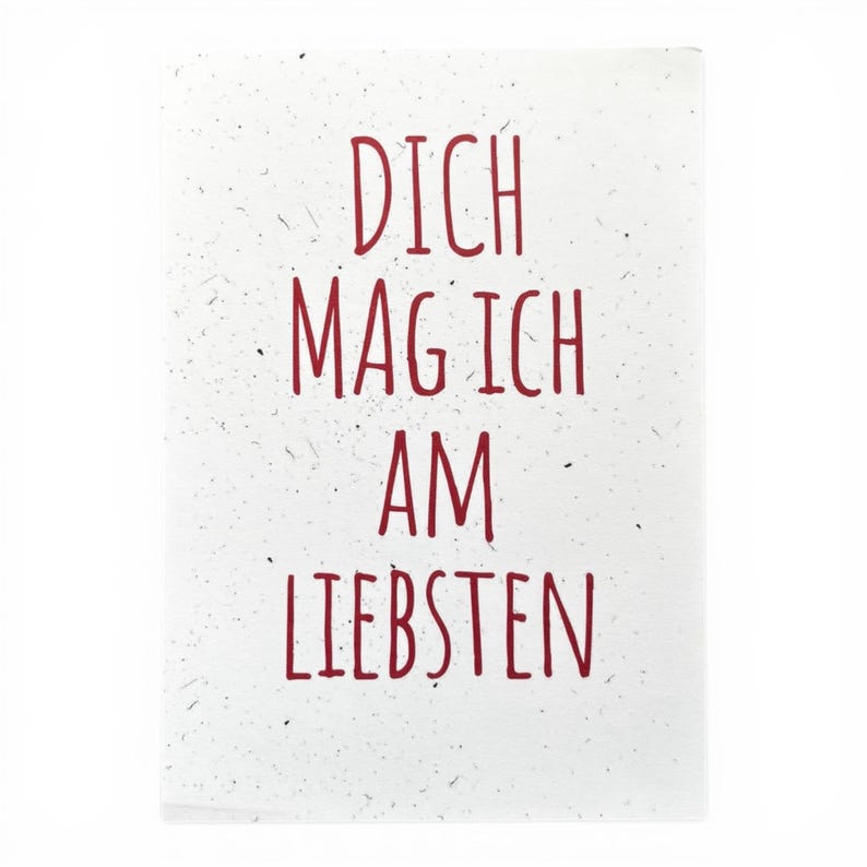 May include: A rectangular white card with a speckled texture featuring the red text DICH MAG ICH AM LIEBSTEN centered in a simple, thin, sans-serif font. The card has a clean, flat surface with visible dark flecks throughout the paper.