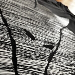 May include: Abstract black and white artwork. The design features a series of thin, horizontal lines with thick, black, vertical strokes and splatters. The artwork is on a white background, with a black fabric draped over it.