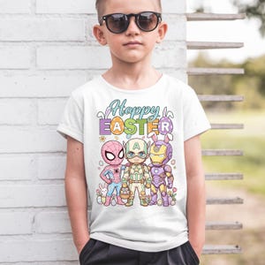 A young boy wearing a white t-shirt with a colorful graphic design featuring cartoon characters and Easter-themed elements.
