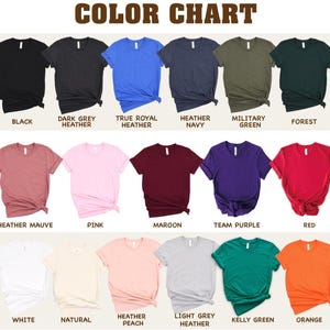 a collection of t-shirts in various colors, including black, dark grey, true royal heather, Heather navy, military green, forest green, maroon, pink, maroon, purple, red, peach, light grey, kerry green, and orange.