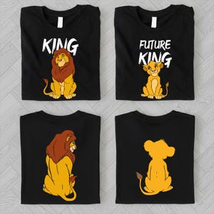 May include: Four black t-shirts with lion graphics. Two shirts have the word "KING" above a lion illustration. The other two shirts have a lion cub graphic and the words "FUTURE KING". The shirts are folded.