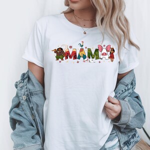 A woman wearing a white t-shirt with colorful text and illustrations, including characters and floral designs.