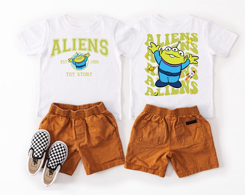 a pair of children's clothing items, including a white t-shirt with a yellow alien character and a pair of brown shorts.