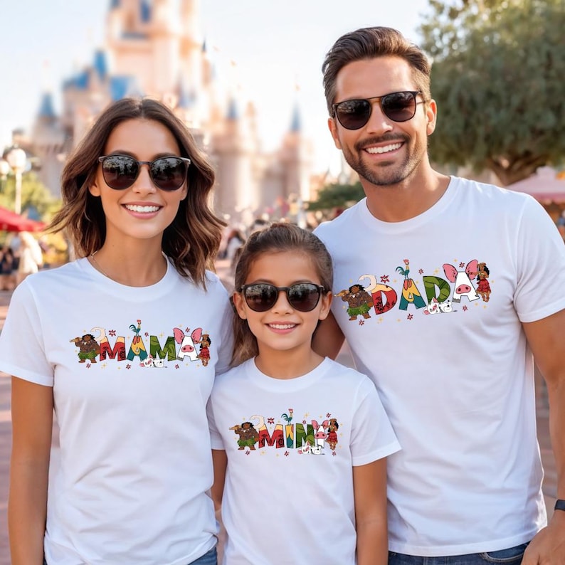 A family of three, consisting of a mother, father, and daughter, is standing together and smiling for a photo. They are all wearing matching white t-shirts with the word "MAMAS" printed on them.