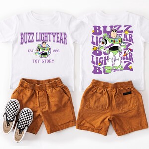 a collection of children's clothing and footwear, including a white t-shirt with a Buzz Lightyear character design, brown shorts, and black and white checkered shoes.