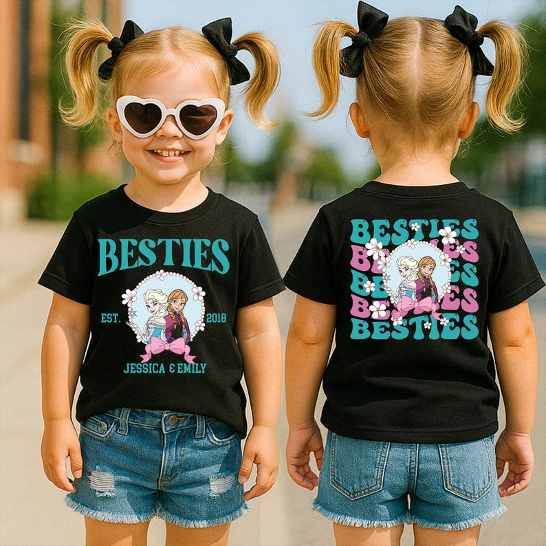 A young girl wearing a black t-shirt with a graphic design and sunglasses, smiling and posing for the camera.