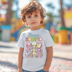 A young boy wearing a white t-shirt with a colorful Easter-themed graphic design featuring cartoon characters.