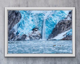 May include: A framed photograph of a glacier with a waterfall cascading down its icy face. The glacier is a vibrant blue color, and the water is a clear turquoise. The photo is taken from a distance, showing the glacier and waterfall in their entirety.