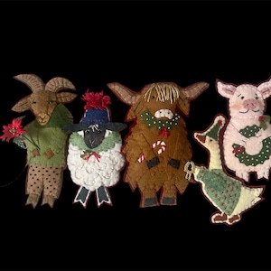 May include: Five felt Christmas ornaments depicting a goat, sheep, cow, goose, and pig. Each ornament is decorated with festive details like holly, candy canes, and bows.