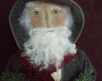 May include: A handmade rag doll dressed as a Christmas gnome. The gnome is wearing a green hooded hat, a red vest, and a white beard. The gnome is holding two sprigs of pine.